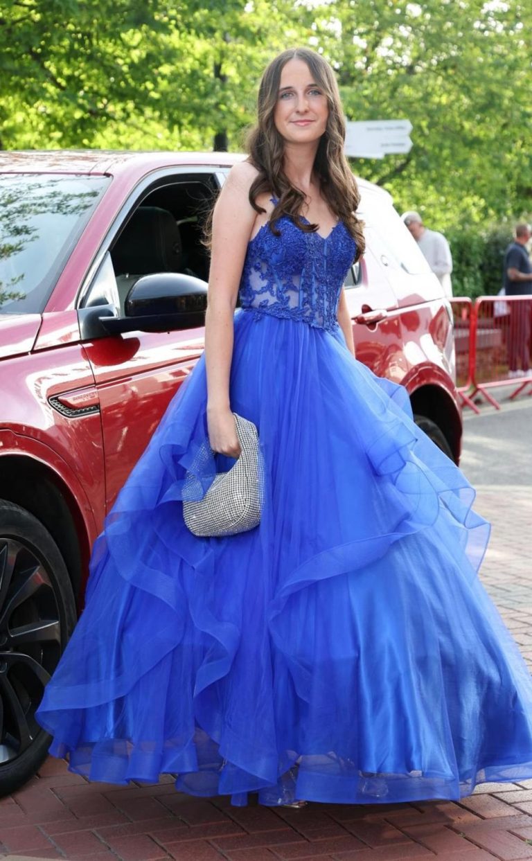 Blue Princess Dress Woman in a blue ball gown holding a silver clutch, standing near a red car.
